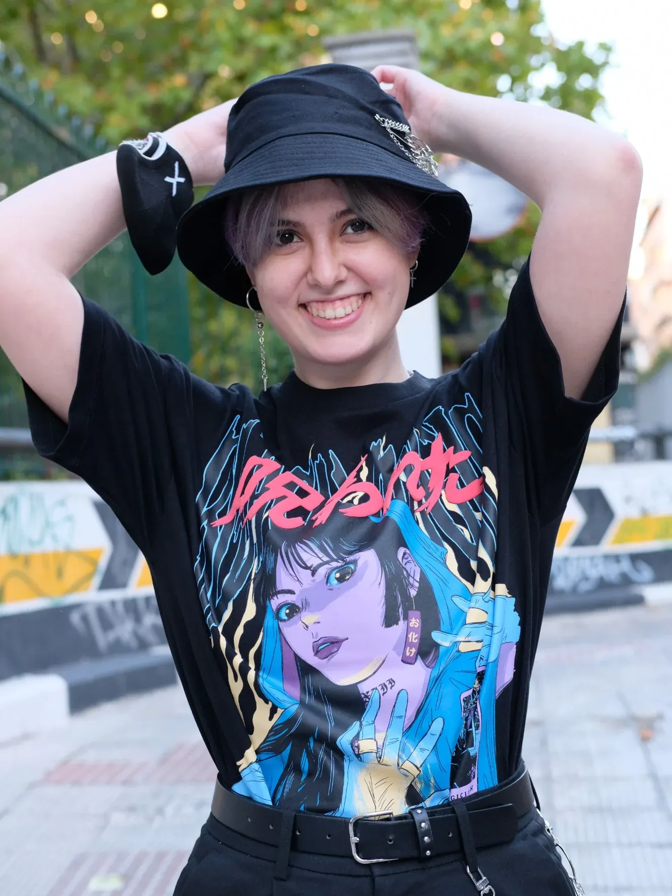 Teresa Costas smiling, hands on a black bucket hat, in an anime-print T-shirt